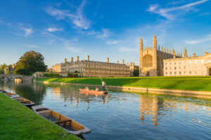 Beautiful view of college in Cambridge with people punting on ri