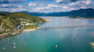 Aerial view of Barmouth Bridge and Afon Mawddach Estuary with boats in bay, Snowdonia, Wales, UK